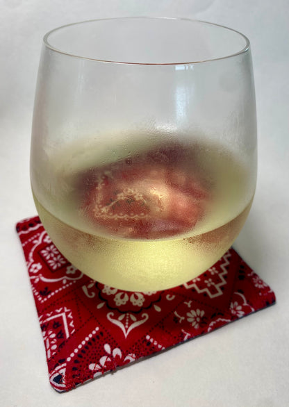 Glass of white wine on a red patterned coaster.